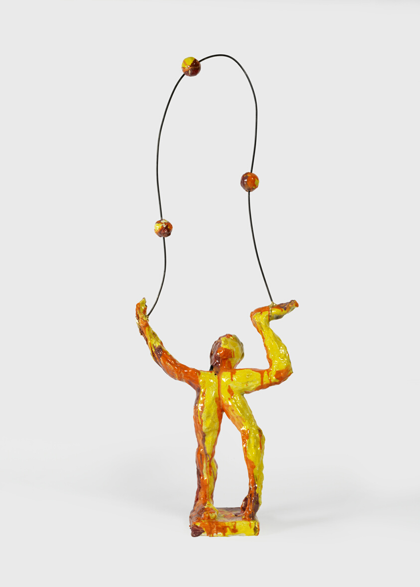 man standing juggling three balls by candlelight